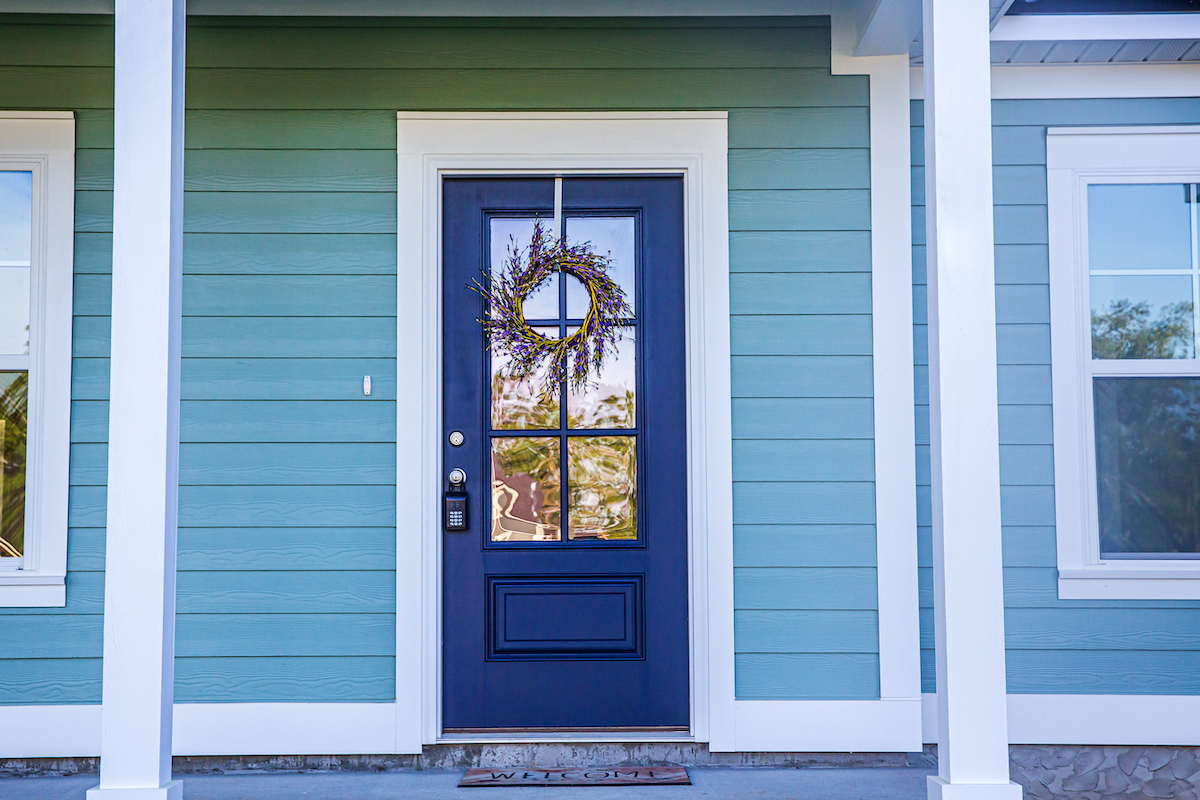 Blue Front Door of a brand new construction house with blue siding, a  ranch style home with a yard