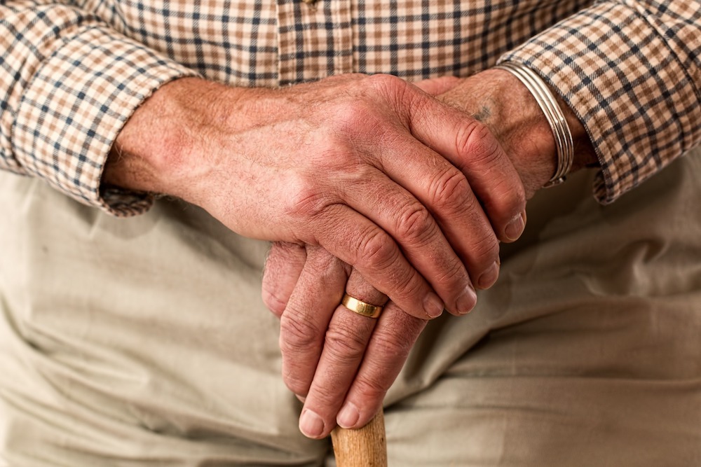 older gentleman with hands over cane